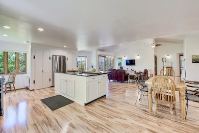 Kitchen featuring dark countertops, light wood-style flooring, open floor plan, white cabinets, and a center island