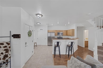 Kitchen featuring appliances with stainless steel finishes, a peninsula, a breakfast bar area, and light tile patterned floors