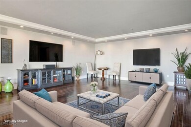 Living room featuring dark wood finished floors, recessed lighting, a raised ceiling, and ornamental molding