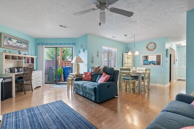 Living room with wood finished floors, ceiling fan, and a textured ceiling