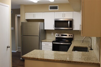 Another view of the modern Kitchen with its stainless steel appliances, granite countertops, and white soft closing cabinetry and drawers.