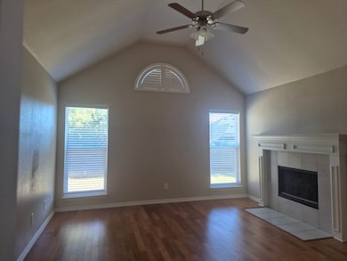 Unfurnished living room with lofted ceiling, dark wood-type flooring, a ceiling fan, and a tile fireplace