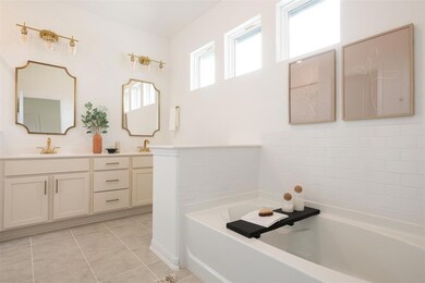 Bathroom with double vanity, a garden tub, and ti