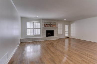 Unfurnished living room featuring healthy amount of natural light, wood finished floors, a brick fireplace, and recessed lighting