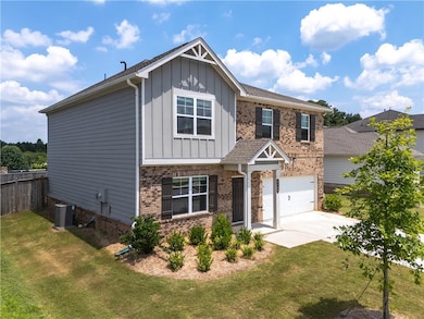 Craftsman-style home with board and batten siding, driveway, brick siding, and an attached garage