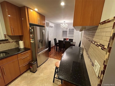 Kitchen featuring backsplash, brown cabinets, stainless steel refrigerator with ice dispenser, dark stone counters, and recessed lighting