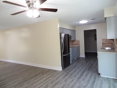 Kitchen featuring backsplash, light countertops, freestanding refrigerator, dark wood-style floors, and a textured ceiling