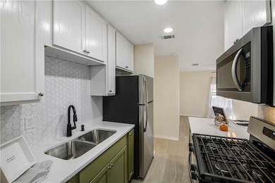 Kitchen with stainless steel appliances, green cabinets, backsplash, white cabinetry, and recessed lighting