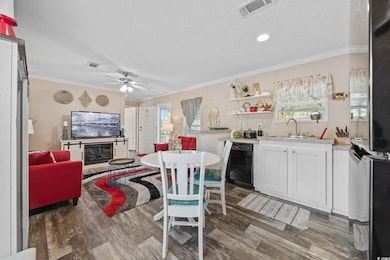 Kitchen featuring black dishwasher, wood finished floors, healthy amount of natural light, a ceiling fan, and crown molding