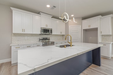 This kitchen features modern white cabinetry, a sp