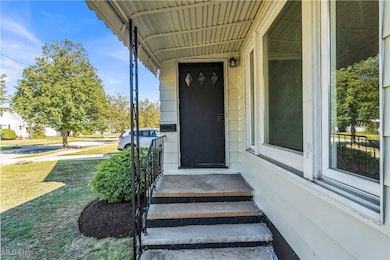 Doorway to property featuring covered porch and a yard