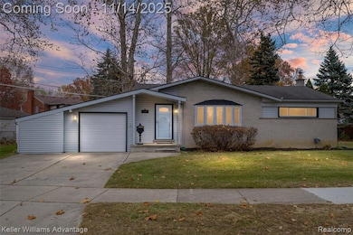 View of front facade featuring a chimney, a lawn, brick siding, concrete driveway, and an attached garage