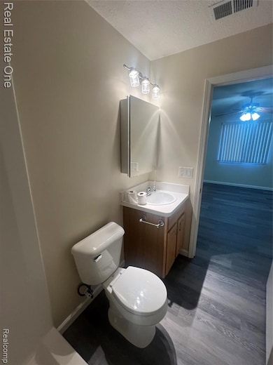 Bathroom featuring vanity, a textured ceiling, light wood-style flooring, and ceiling fan