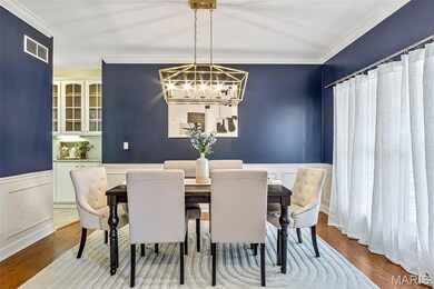 Dining area featuring ornamental molding, a chandelier, a wainscoted wall, and wood finished floors