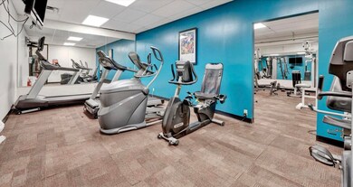 Exercise room with a drop ceiling and light carpet