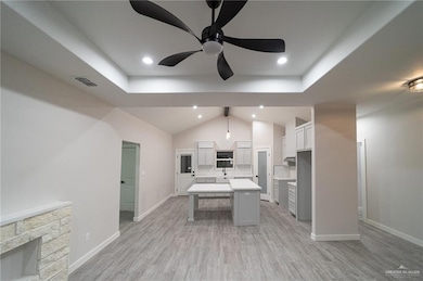 Kitchen with light wood-style flooring, gray cabinetry, a center island, ceiling fan, and a breakfast bar