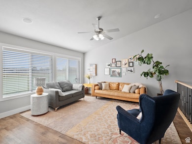 Living room with lofted ceiling, wood finished floors, and ceiling fan