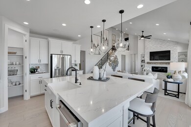 Kitchen featuring open floor plan, a stone fireplace, white cabinetry, decorative light fixtures, and light stone countertops