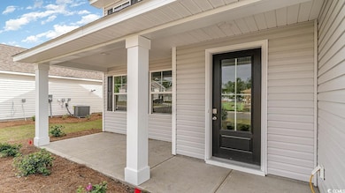 Property entrance featuring central AC and covered