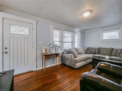 Hardwood floored living room with a wealth of natural light, ornamental molding, and a textured ceiling