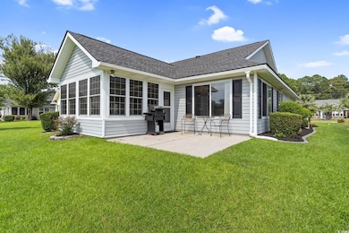 Rear view of property featuring a patio area, a shingled roof, and a lawn