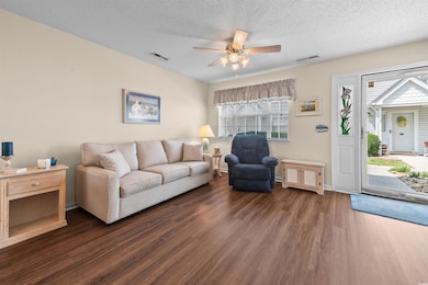 Living area with dark wood-type flooring, ceiling fan, a textured ceiling, and baseboards