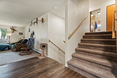 Stairs featuring wood finished floors and a baseboard heating unit