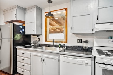 Kitchen featuring white appliances, a sink, under