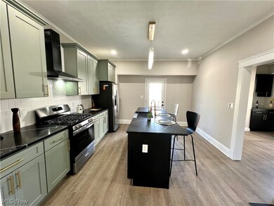 Kitchen with a kitchen breakfast bar, wall chimney range hood, light hardwood / wood-style flooring, appliances with stainless steel finishes, and backsplash