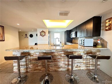 Kitchen with sink, tasteful backsplash, light stone counters, light tile floors, and kitchen peninsula