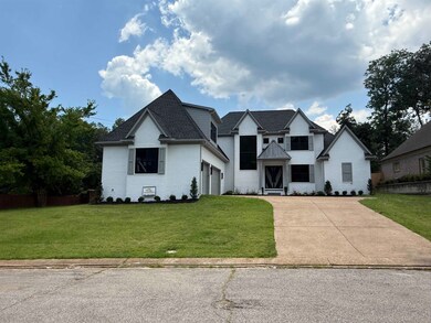 View of front facade featuring a front lawn, concrete driveway, a garage, and brick siding
