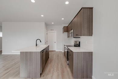 Kitchen with modern cabinets, appliances with stainless steel finishes, recessed lighting, a kitchen island with sink, and light wood finished floors