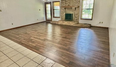 Unfurnished living room featuring wood-type flooring and a brick fireplace