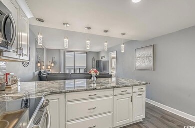 Kitchen featuring stainless steel appliances, light stone countertops, open floor plan, white cabinets, and a peninsula