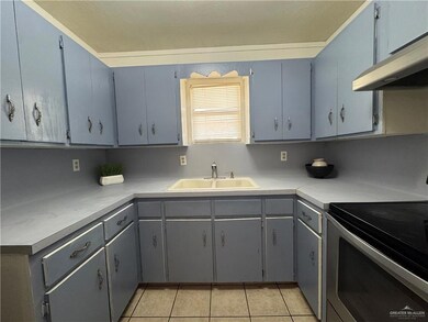 Kitchen featuring a sink, stainless steel electric stove, under cabinet range hood, light tile patterned flooring, and light countertops