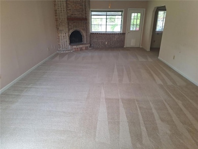 Unfurnished living room with carpet flooring, a brick fireplace, lofted ceiling, a sunroom, and visible vents