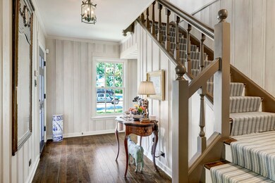 Bright entry maintains original feel with color-washed original wood paneling and original pegged, wide-plank flooring. Custom stair runner.