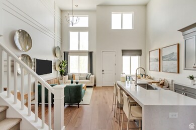 PHOTO FROM SIMILAR MODEL HOME. COLORS, OPTIONS, AND FEATURES WILL VARY: Living room featuring light wood-style flooring, stairway, and a towering ceiling