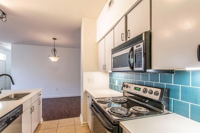 Kitchen with white cabinetry, light countertops, 