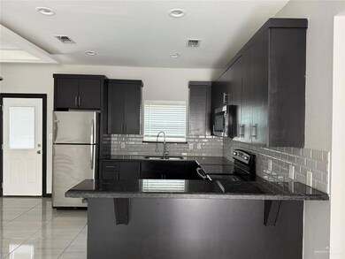 Kitchen featuring stainless steel appliances, a peninsula, a sink, visible vents, and dark cabinetry