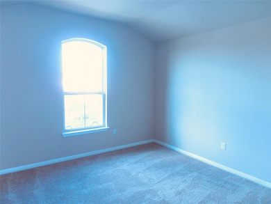 Carpeted spare room featuring vaulted ceiling