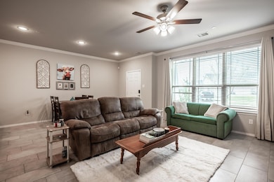 Living room with a healthy amount of sunlight, ornamental molding, light tile flooring, and ceiling fan
