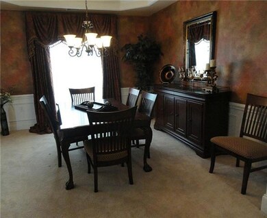 Dining room with trey ceiling, decorative lighting, decorative wainscoting and plush carpeting. 