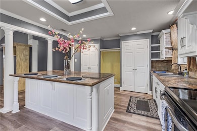 Kitchen featuring white cabinets, recessed lighting, crown molding, electric stove, and a raised ceiling
