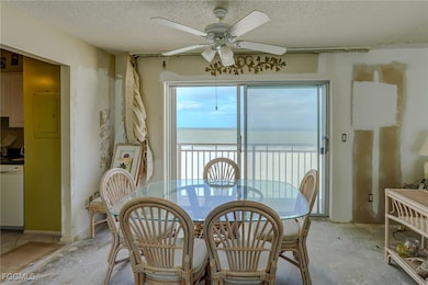 Dining area with a water view, a textured ceiling, electric panel, and ceiling fan