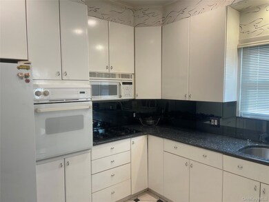 Kitchen with white appliances, dark stone countertops, and white cabinets