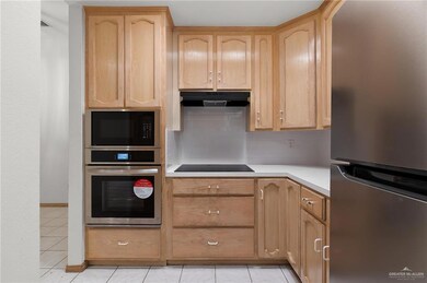 Kitchen featuring appliances with stainless steel finishes, light tile patterned flooring, backsplash, and light brown cabinets