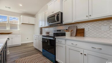 Kitchen with white cabinetry, light countertops, v