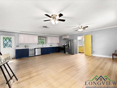 Kitchen featuring stainless steel appliances, light countertops, crown molding, ceiling fan, and light wood-type flooring