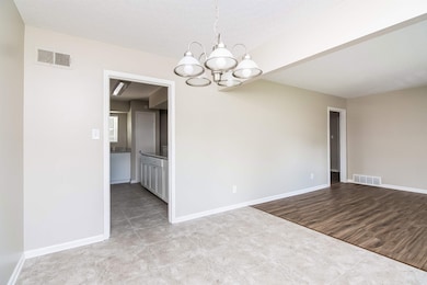 Unfurnished room featuring a chandelier, baseboards, and tile patterned flooring